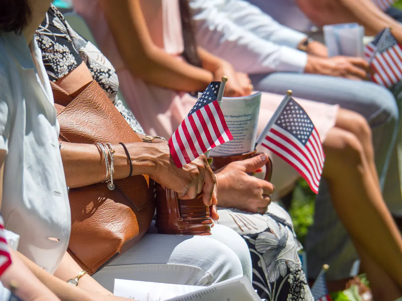 67dc26fc67b49_flag-5347106_1280 A group of people sitting in the sun holding american flags.